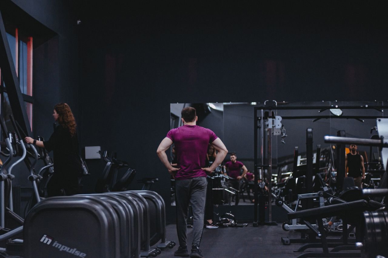 Man in a gym with fitness equipment, highlighting a healthy lifestyle.