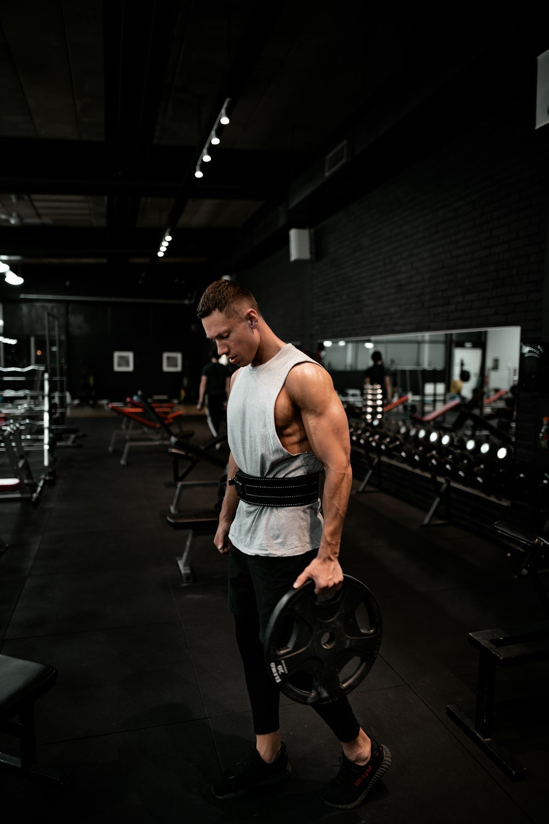 about-04 man-in-white-tank-top-holding-bumper-plate-tazoumdqzxk